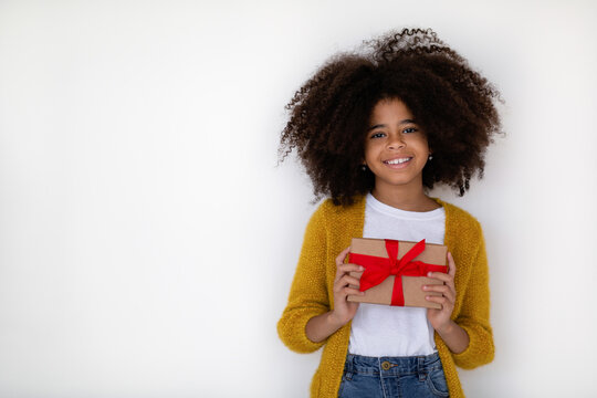 Excited black girl holding red gift box on white