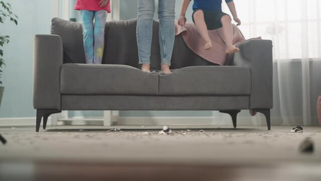Little boy gets down from sofa jumping amazed by coins amount with family in living room closeup slow motion. Breaking piggy bank to output money