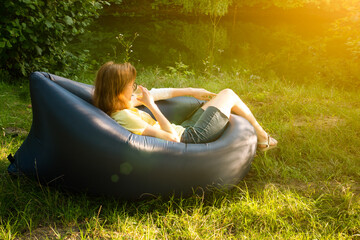 Woman relaxing on Inflatable sofa out in the wild camping..Air Sofa or Lamzac on the nature.