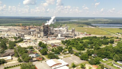 Industrial paper mill beside river with smoke stacks billowing pollution into the environment