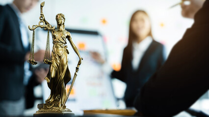 Statue of justice with scales, the team meeting at the law firm behind the concept of in office law. - obrazy, fototapety, plakaty