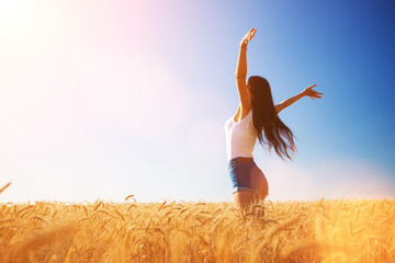 Happy woman enjoying the life in the field. Nature beauty, blue sky, white clouds and field with golden wheat. Outdoor lifestyle. Freedom concept. Woman jump in summer field - 528736421