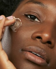 Black woman putting shea butter on her face