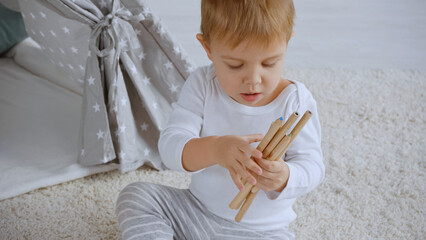 concentrated toddler boy holding color pencil and sitting on carpet near baby wigwam © LIGHTFIELD STUDIOS