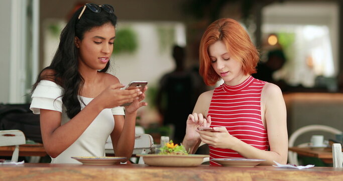 Diverse young women taking photo of food plate showing scren