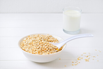 bowl of granola with a spoon and a glass of oat milk. white wooden background. top view. copy space.