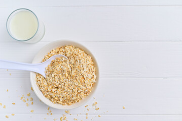 bowl of granola with a spoon and a glass of oat milk. white wooden background. top view. copy space.