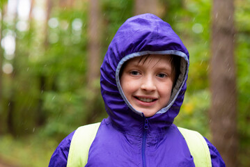 happy child walking on a rainy day in the forest