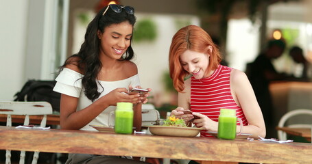 Friend showing cellphone screen to girl, candid and casual of two beautiful diverse friendship