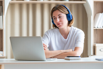 Young attractive woman in headphones studying online at home. Distance education concept	
