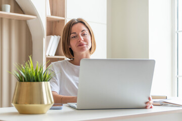 Young female student sitting at the desk at home and preparing for a new academic year. Education and online training concept