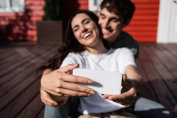 Blurred young couple using smartphone on terrace outdoors