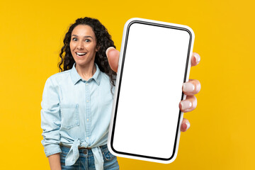 Excited Woman Showing Large Cellphone Blank Screen Over Yellow Background