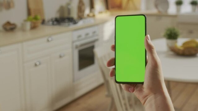 Handheld Camera: Point of View of Man at Kitchen Room Using Phone With Green Mock-up Screen Chroma Key Without Track Points Surfing Internet Watching Content Videos Blogs. Swiping Left Twice.