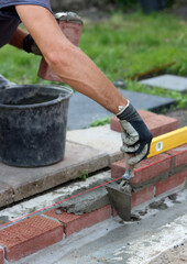 Close up photo of male hands holding red brick. Construction site concept. Professional build brick wall. 