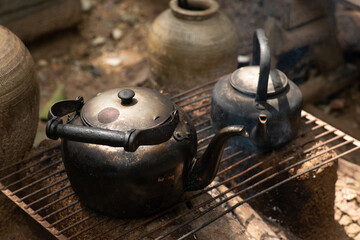 black vintage kettle warming on traditional fireplace in country home Thailand style with morning light