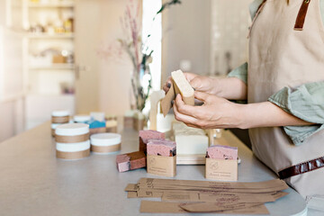 A soap maker girl holds a piece of freshly brewed handmade soap in her hands.The process of...
