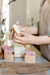 A soap maker girl holds a piece of freshly brewed handmade soap in her hands.The process of preparation and packaging.Home spa.Small business