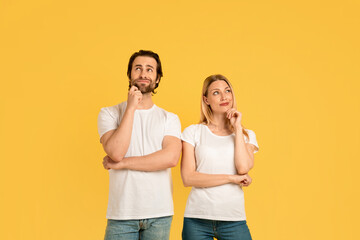 Fototapeta premium Pensive millennial caucasian male and woman in white t-shirts think and look up at empty space
