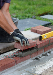 Close up photo of male hands holding red brick. Construction site concept. Professional build brick wall. 