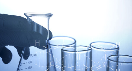 Naklejka premium hand of scientist holding flask with lab glassware and test tubes in chemical laboratory background, science laboratory research and development concept
