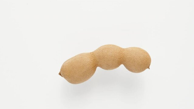 A single tamarind rotates on a white background top view, close-up.
