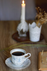 Cup of tea, plate with chocolate chip cookies, open book, reading glasses, lit candles and dry lavender flowers. Hygge at home, selective focus.