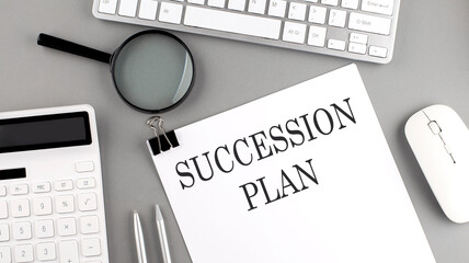 SUCCESSION PLAN written on paper with office tools and keyboard on the grey background
