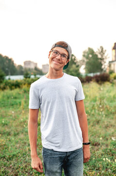 Portrait of a cute Caucasian guy with glasses and a cap outdoors in summer. The teenager looks at the camera with wide eyes. stock image