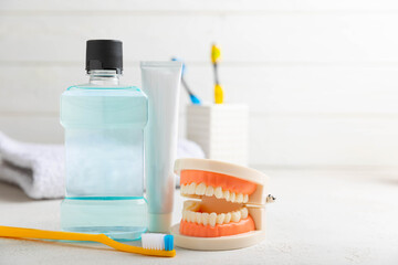 Toothbrush, tongue cleaner, dental floss, tube of toothpaste and mouthwash with false teeth model on white background with copy space. Flat lay. Oral hygiene. Oral Care Kit. Dentist concept.