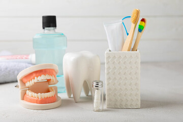 Fototapeta na wymiar Toothbrush, tongue cleaner, dental floss, tube of toothpaste and mouthwash with false teeth model on white background with copy space. Flat lay. Oral hygiene. Oral Care Kit. Dentist concept.
