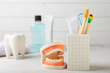 Toothbrush, tongue cleaner, dental floss, tube of toothpaste and mouthwash with false teeth model on white background with copy space. Flat lay. Oral hygiene. Oral Care Kit. Dentist concept.