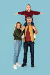 Mother And Father Posing, Holding Daughter On Shoulders, Blue Background