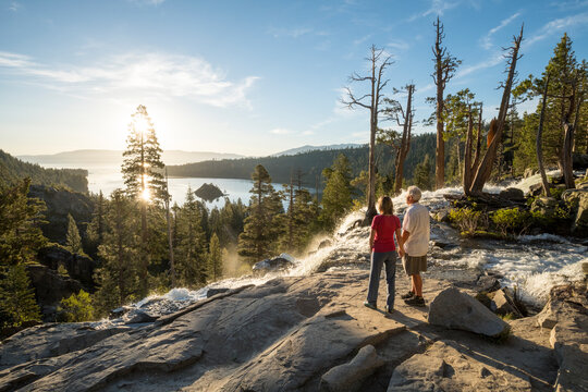 A man and a woman hold hands at the top of Eagle Falls at sunrise.