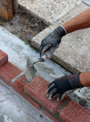Close up photo of male hands holding red brick. Construction site concept. Professional build brick wall. 