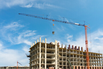 Unfinished cement building at a construction site. Large construction crane.