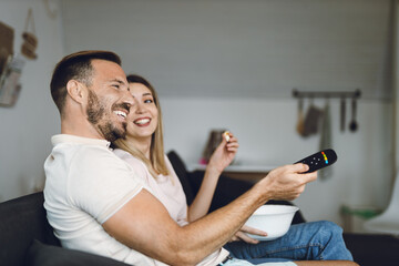 Happy young couple relaxing at home and watching television together