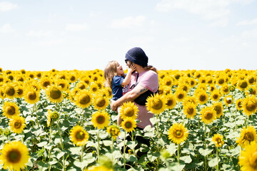 Dad and son hug and laugh in the sunflowers. Father's Day. The concept of family relationships and active recreation. Close-up portrait.