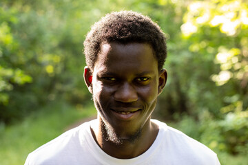 Portrait of an african american man against the background of a green forest.