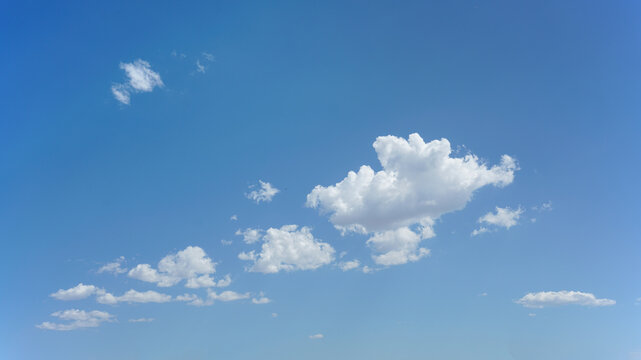 Sparse puffy clouds and blue sky for background use or sky substitution