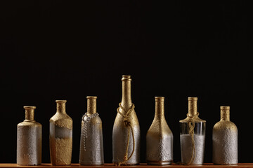 A row of homemade bottle vases on a dark background. Home decorative art.