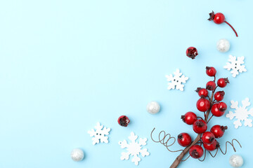 Winter composition with decorative branches on light blue background, flat lay. Space for text