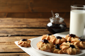 Tasty shortbread cookies with jam on wooden table. Space for text