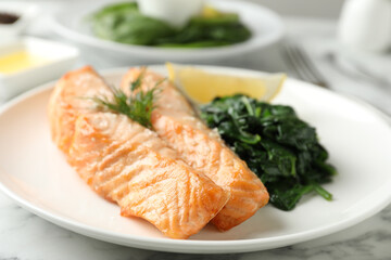 Tasty salmon with spinach and lemon on table