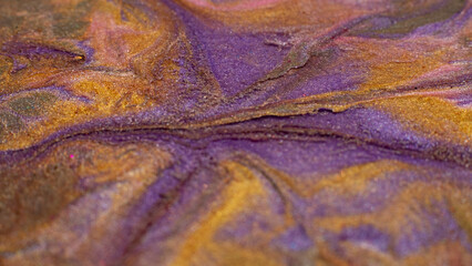 Mixing colors. Fluid magic. Creative painting. Purple orangeglitter liquid paint blend