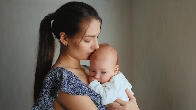 Young Mother Holding her Newborn Sleeping Child. Family at home, woman with baby.