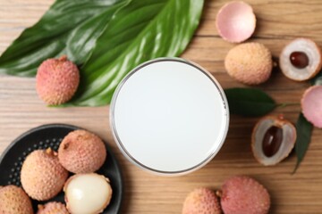 Fresh lychee juice and fruits on wooden table, flat lay