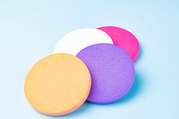 Colorful cosmetic makeup applicator sponge set on blue background.
