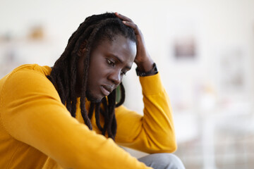 Closeup Portrait Of Depressed African American Guy Sitting At Home