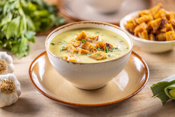 Garlic cream soup with bread croutons in rustic bowl